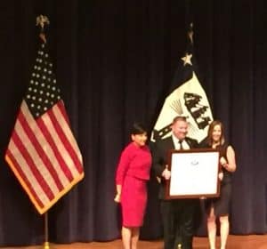 Michael Myhre, Florida SBDC CEO and Network State Director, and Debbie Bernard, International Trade Specialist for the FSBDC at Palm Beach State College (right), accept the award from Secretary Pritzker (left)